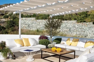 A beige plastic rug with white furniture beneath a pergola - An example of one of the best plastic outdoor rugs