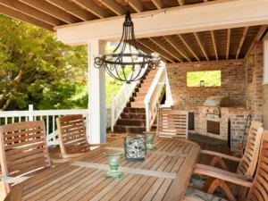 Pergola lighting ideas - An outdoor chandelier hanging from a center beam above an outdoor dining area