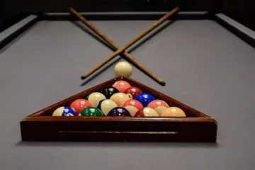 Cue balls in triangle rack with 2 cue sticks - Affordable Pool Tables
